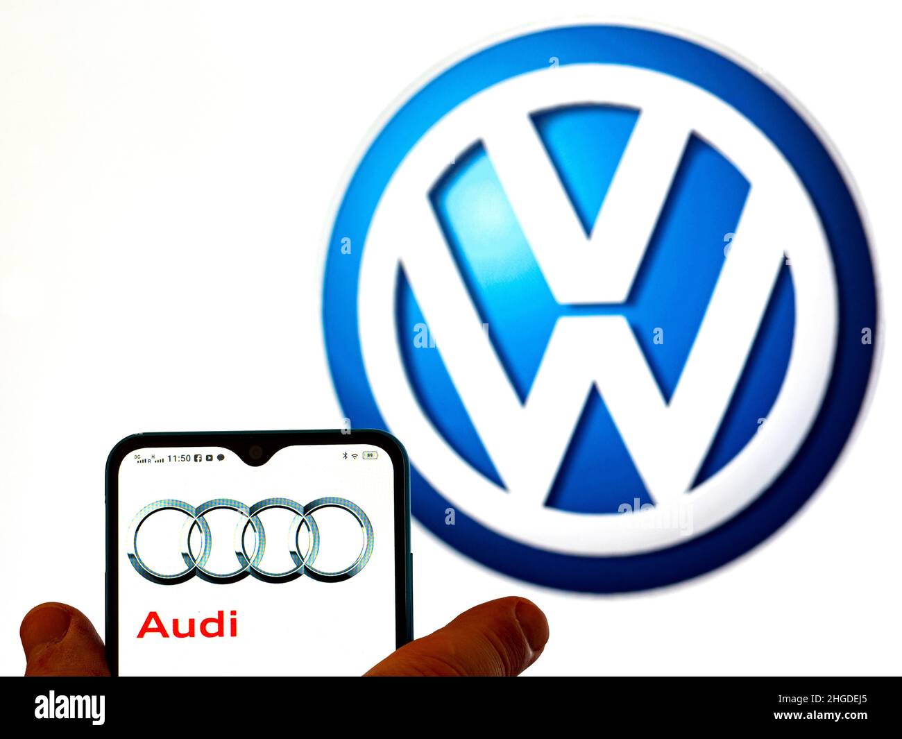 In dieser Abbildung ist das Audi-Logo auf einem Smartphone-Bildschirm mit dem Volkswagen AG-Logo im Hintergrund zu sehen. Stockfoto