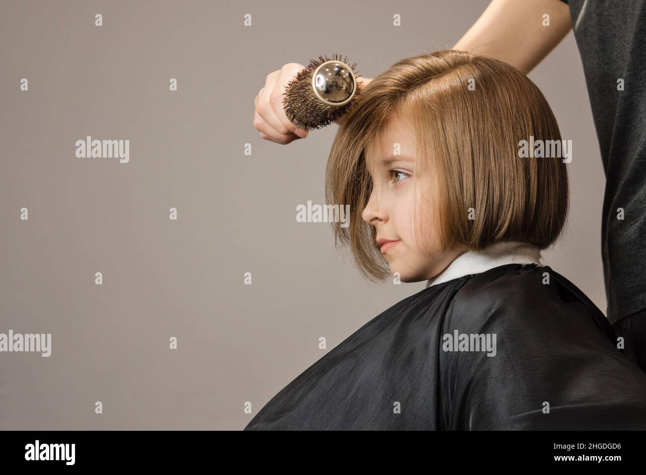 Bob Kurze Frisur. Schönes Haar des kleinen Mädchens. Modischer, Trendiger Haarschnitt. Dark Blonde Kind Modell mit glänzenden Frisur. Haarstyling-Prozess von Hairtician. Kurse im Friseursalon. Schönheitsbehandlungen. Stockfoto