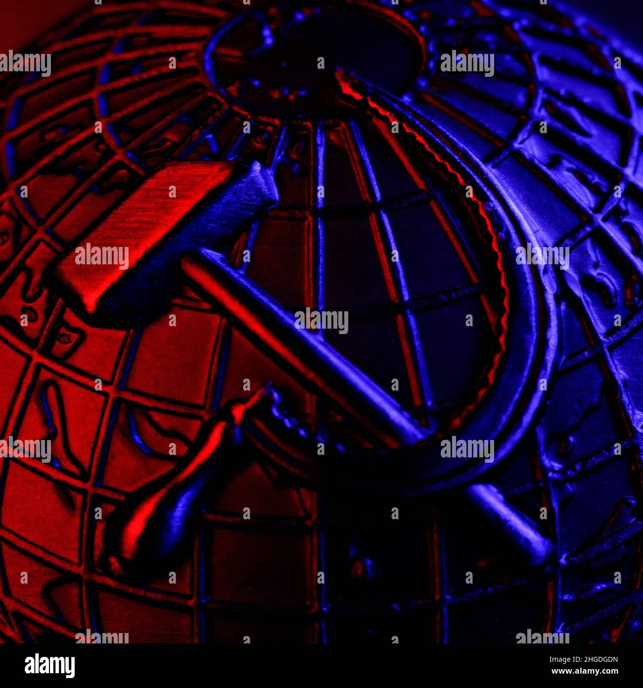 Metallisches Wappen der UdSSR mit Hammer und Sichel auf dem Hintergrund des Erdballs. Symbol des Kommunismus und des Sozialismus. Gewaltige und mächtige Weltmacht. Vorgänger des Landes Russland. Dunkler Hintergrund. Nahaufnahme. Stockfoto