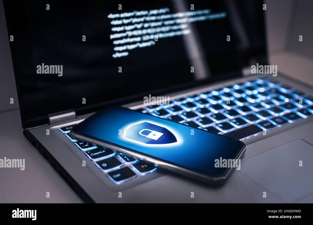 Telefonsperre zum Schutz vor Cyberbetrug, Online-Datenbetrug oder Identitätsdiebstahl. Laptop mit Hacker-Virencode auf dem Bildschirm. Phishing, Cybersicherheitsgefahr. Stockfoto