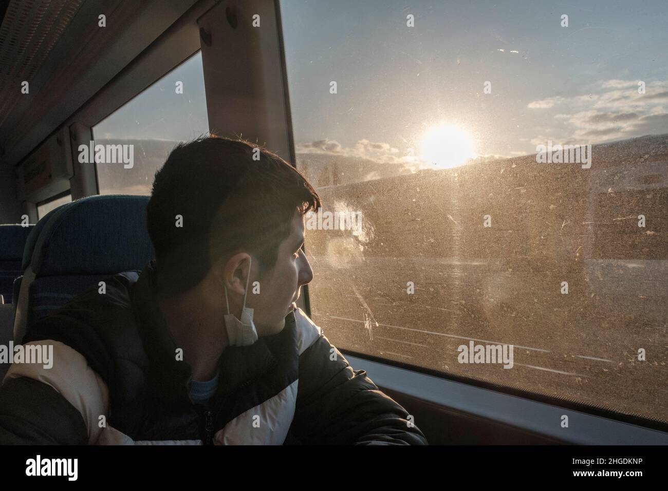 Teenager mit Gesichtsmaske unter seinem Kinn im Zug von Suburban, Soiuthern Rail, South London, Großbritannien Stockfoto