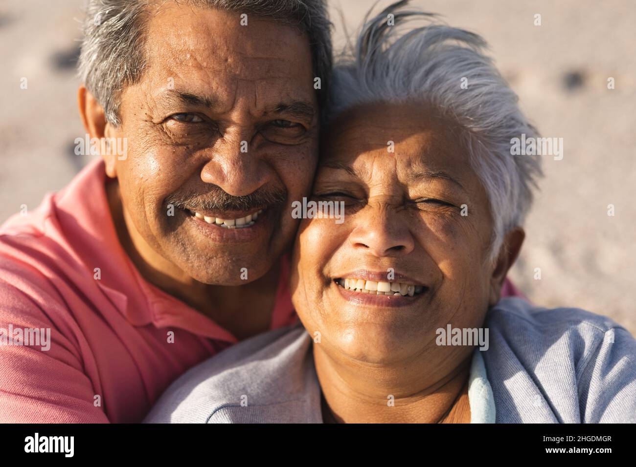Porträt eines lächelnden, mehrrassischen Seniorenpaares, das an sonnigen Tagen gemeinsam am Strand in den Ruhestand geht Stockfoto