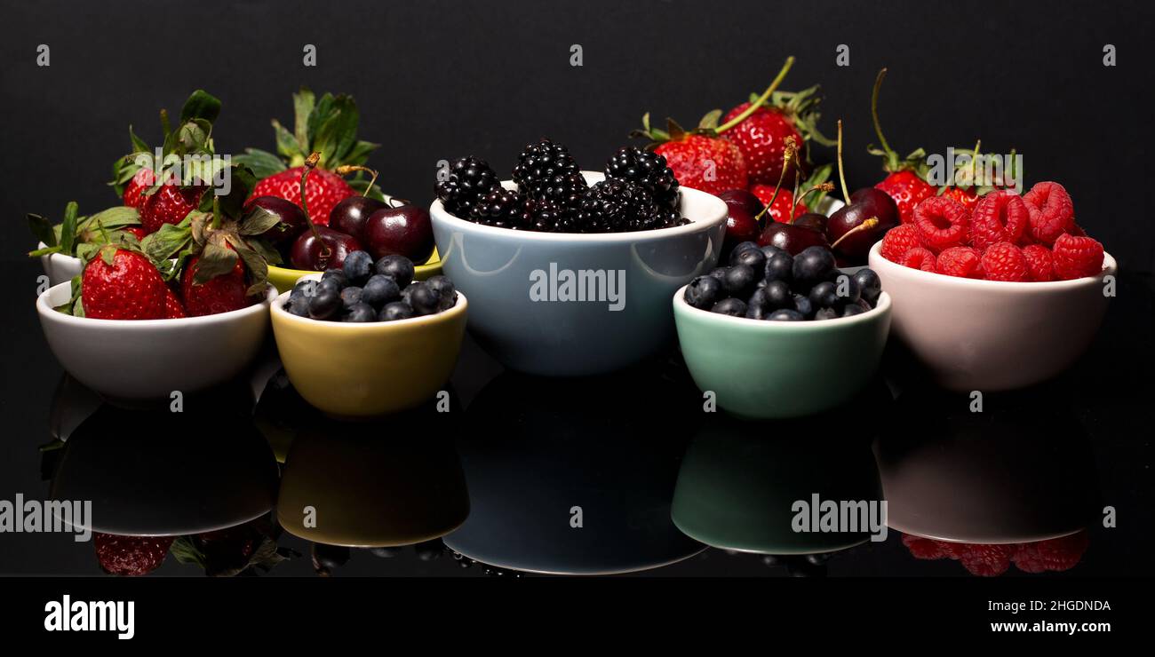 Kirschen und Beeren auf dunklem Hintergrund Stockfoto