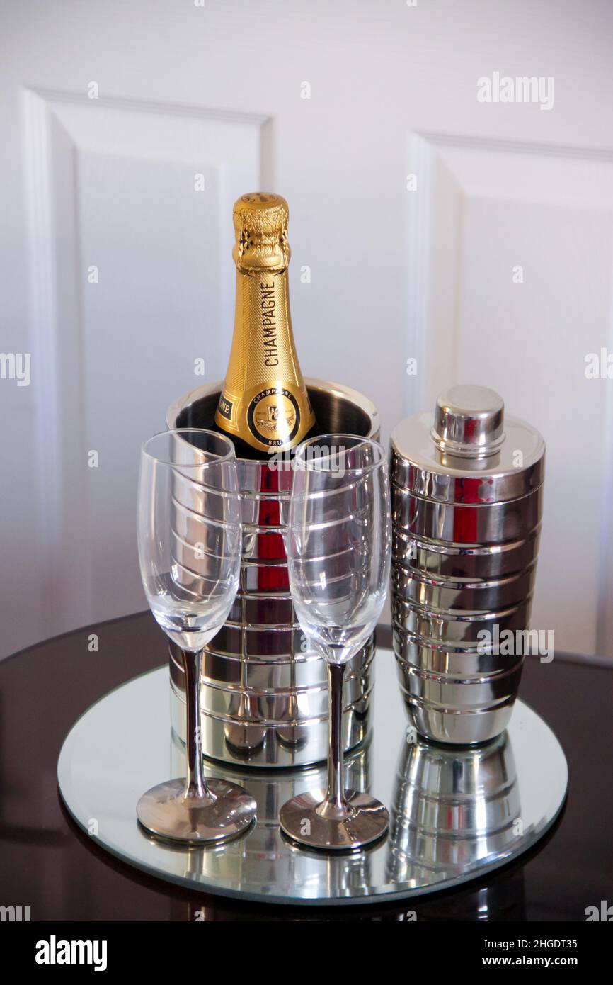 Champage-Flöten, Champagnerflasche im Weinkühler mit Cocktailshaker auf einem verchromten Disc-Tablett, Stockfoto