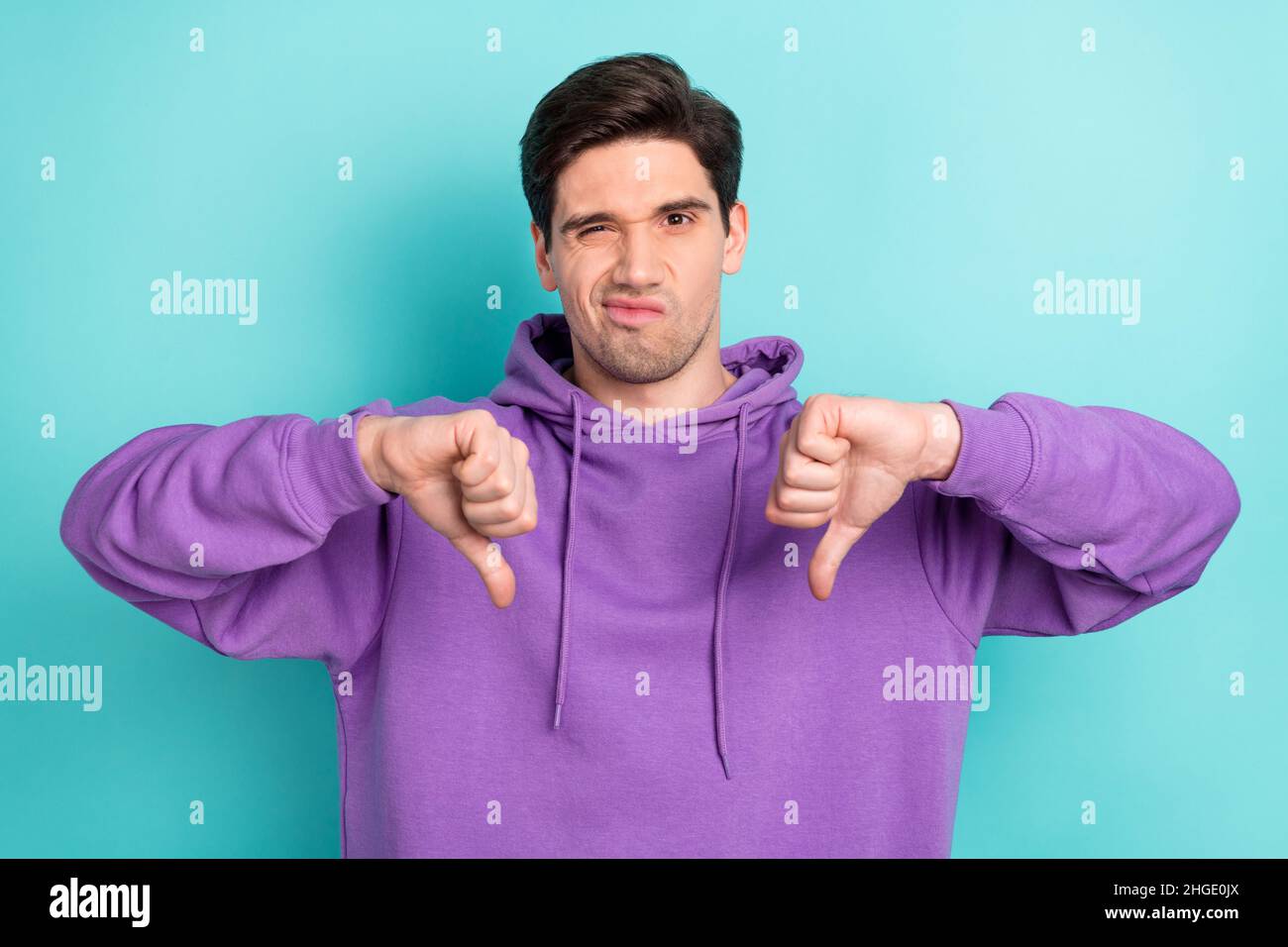 Foto von unglücklichen negativen Stimmung männlichen Grimacing zeigt Daumen nach unten keine Empfehlung isoliert auf blauem Hintergrund Stockfoto