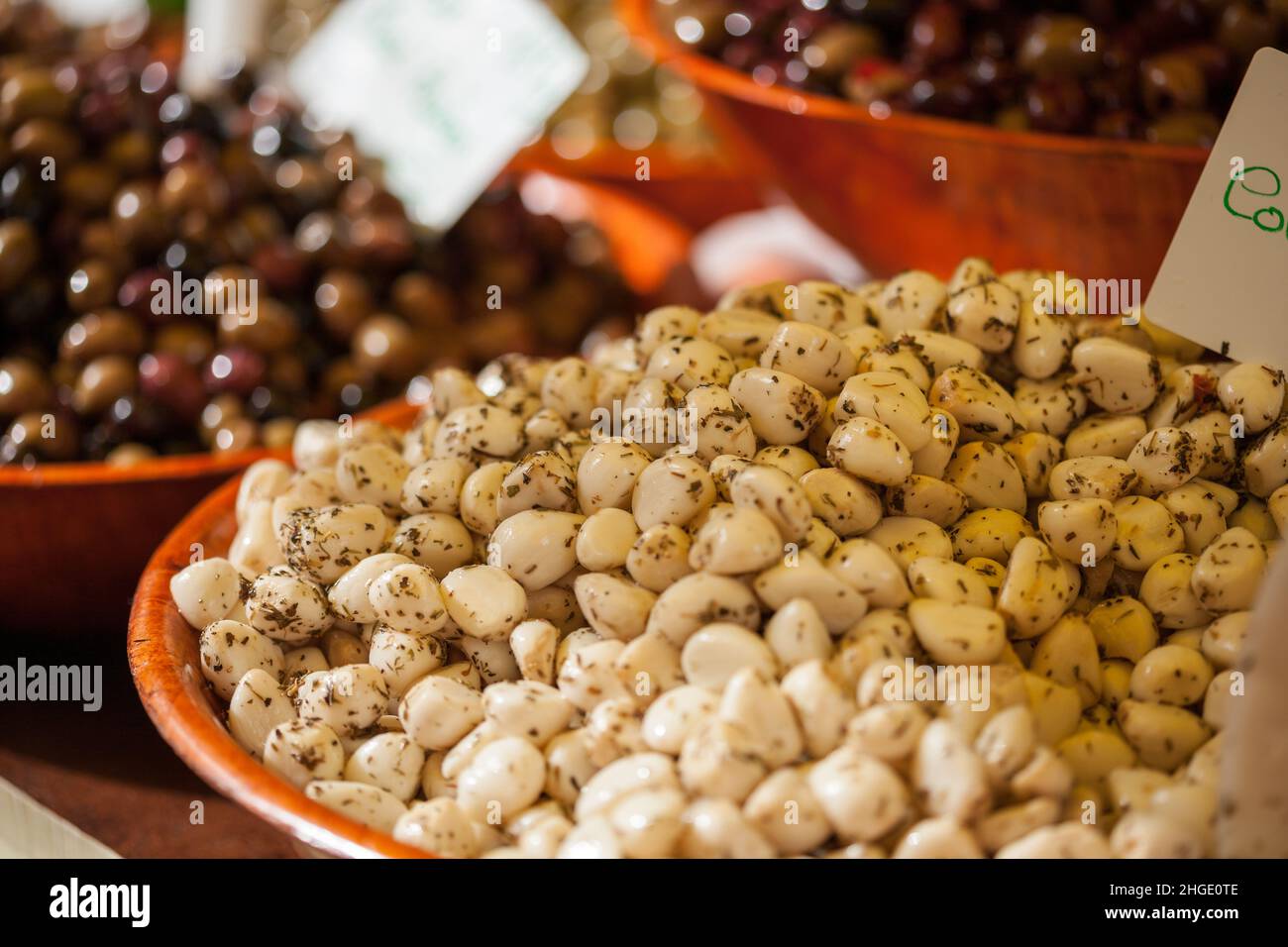 Auf einem französischen Markt werden Schalen mit marinierten Knoblauchzehen und Oliven verkauft Stockfoto