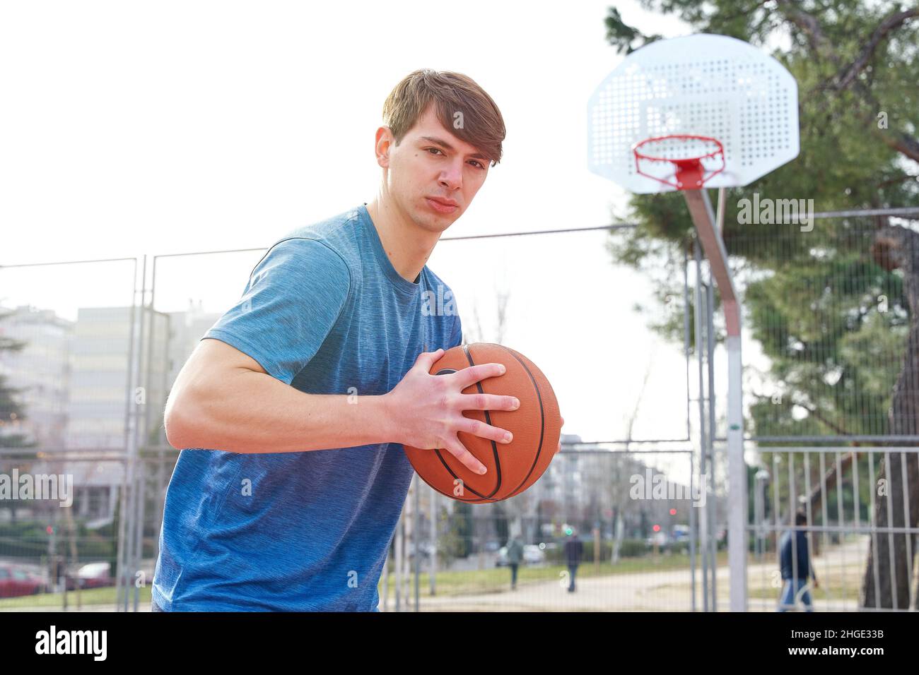 Junger Sportler trainiert auf einem Basketballplatz im Freien. kaukasischer Mann in Sportbekleidung spielt Basketball. Stockfoto