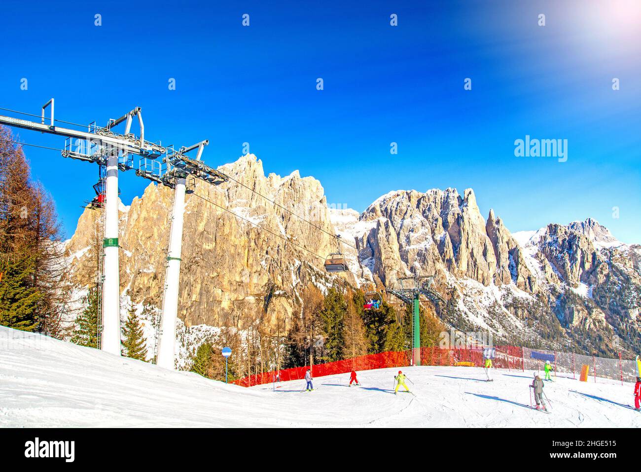 Winterlandschaft in den Dolomiten, Italien, Skipiste mit Skifahrer und Skilift im Val di Fassa Ciampedie mit Bergkette im Hintergrund, Vigo di Stockfoto