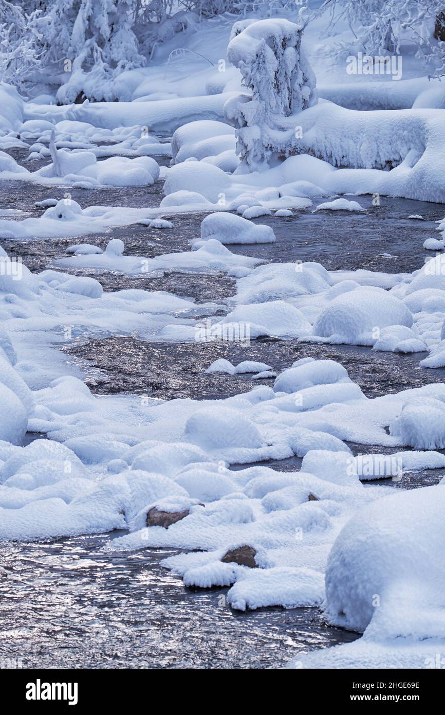 Foto von Steinen mit Schneekappen und Eis im Wasser des gefrorenen Flusses Pescherka in der Nähe von Wasserfall in der Wintersaison. Sibirien, Russland Stockfoto