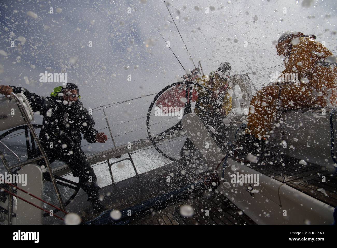 Eine große Welle stürzt über das Achterdeck einer Segelyacht im Ärmelkanal ab, die die Crew einweicht Stockfoto
