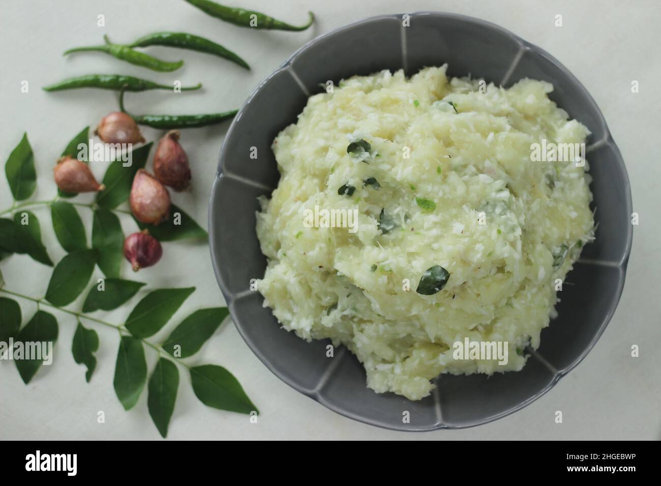 Zermalmter Tapioka mit grünen Chilischoten und Schalotten. Beliebtes Gericht von Kerala gemeinhin als Kappa vevichathu. Aufgenommen auf weißem Hintergrund Stockfoto