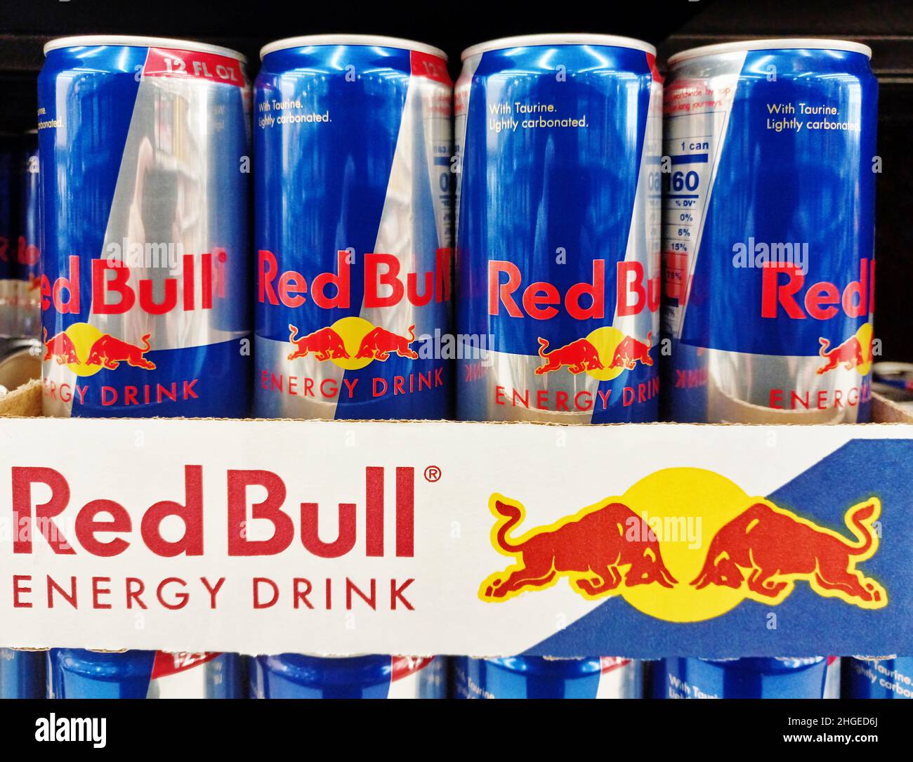 Houston, Texas USA 01-06-2022: Red Bull Energy-Drink-Dosen Reihen sich auf einem Supermarktregal mit schwarzem Hintergrund an. Stockfoto