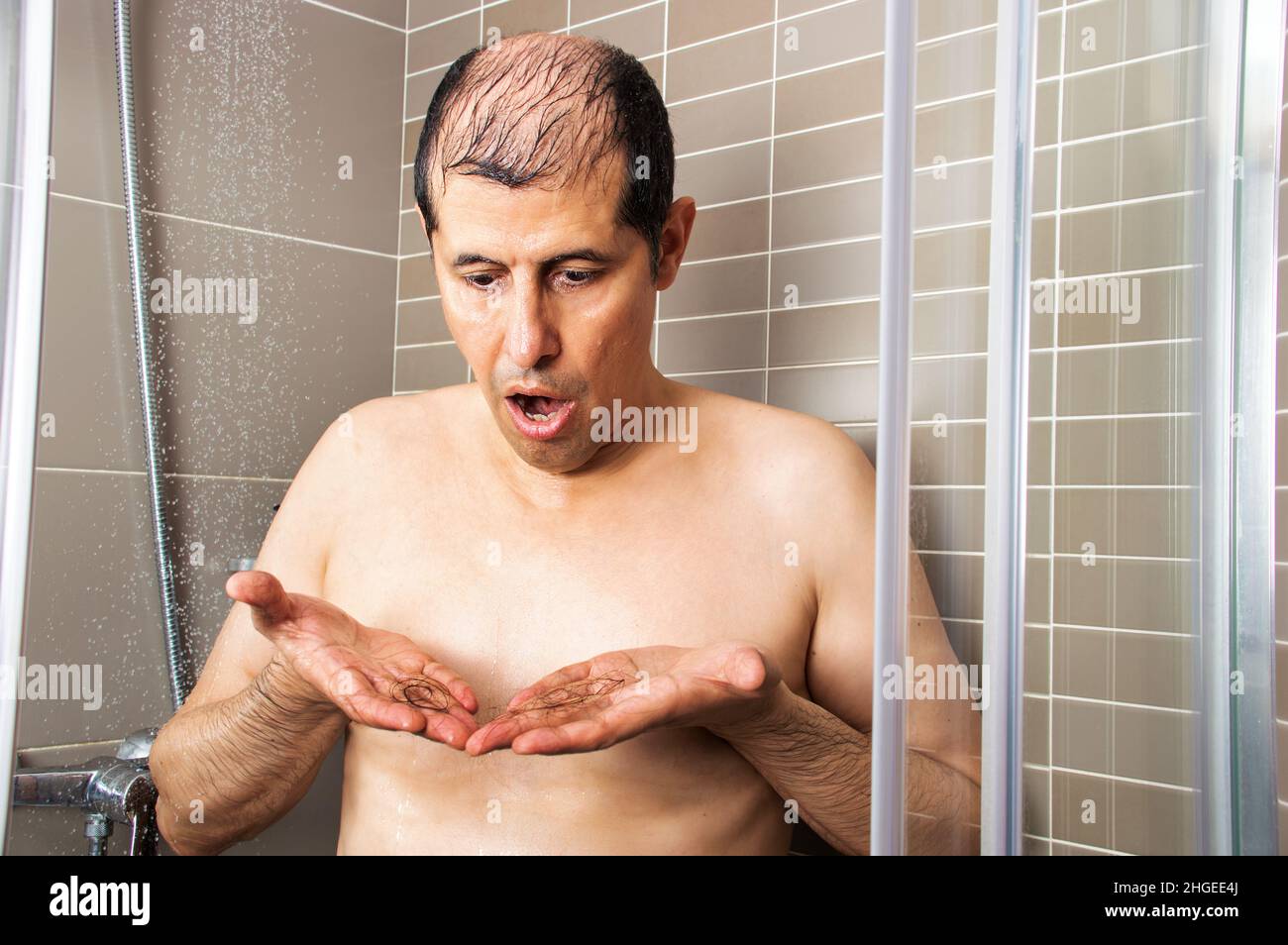 Mann duscht und überprüft, ob seine Haare herausfallen Stockfoto