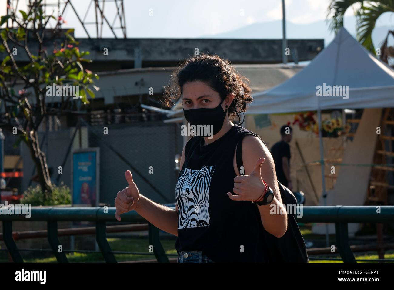Medellin, Antioquia, Kolumbien - Dezember 7 2021: Lockige Frau mit schwarzer Maske winkt mit den Händen Stockfoto