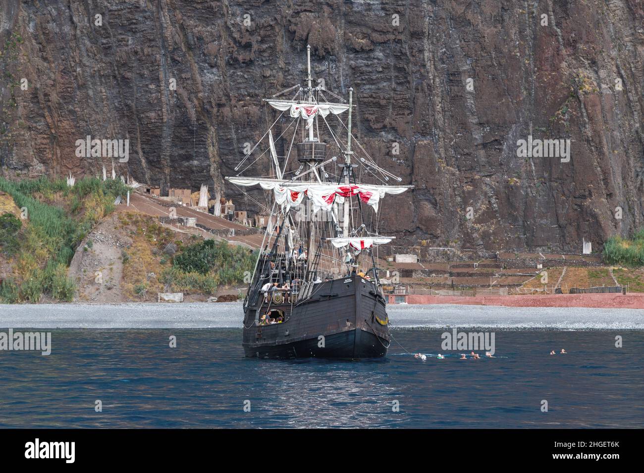 MADEIRA, PORTUGAL - 25. AUGUST 2021: Dies ist ein Vergnügungsboot in Form der historischen Santa Maria Karavelle mit Urlaubern an den felsigen Ufern von Stockfoto MADEIRA, PORTUGAL - 25. AUGUST 2021: Dies ist ein Vergnügungsboot in Form der historischen Santa Maria Karavelle mit Urlaubern an den felsigen Ufern von Stockfoto