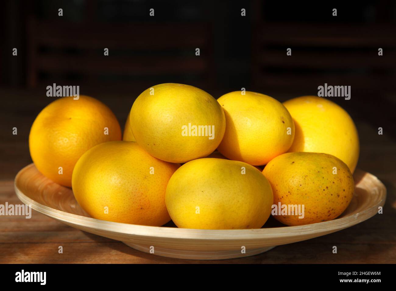 Grapefruits. Gelbe reife Grapefruits auf Holzplatte und auf schwarzem Hintergrund. Stockfoto