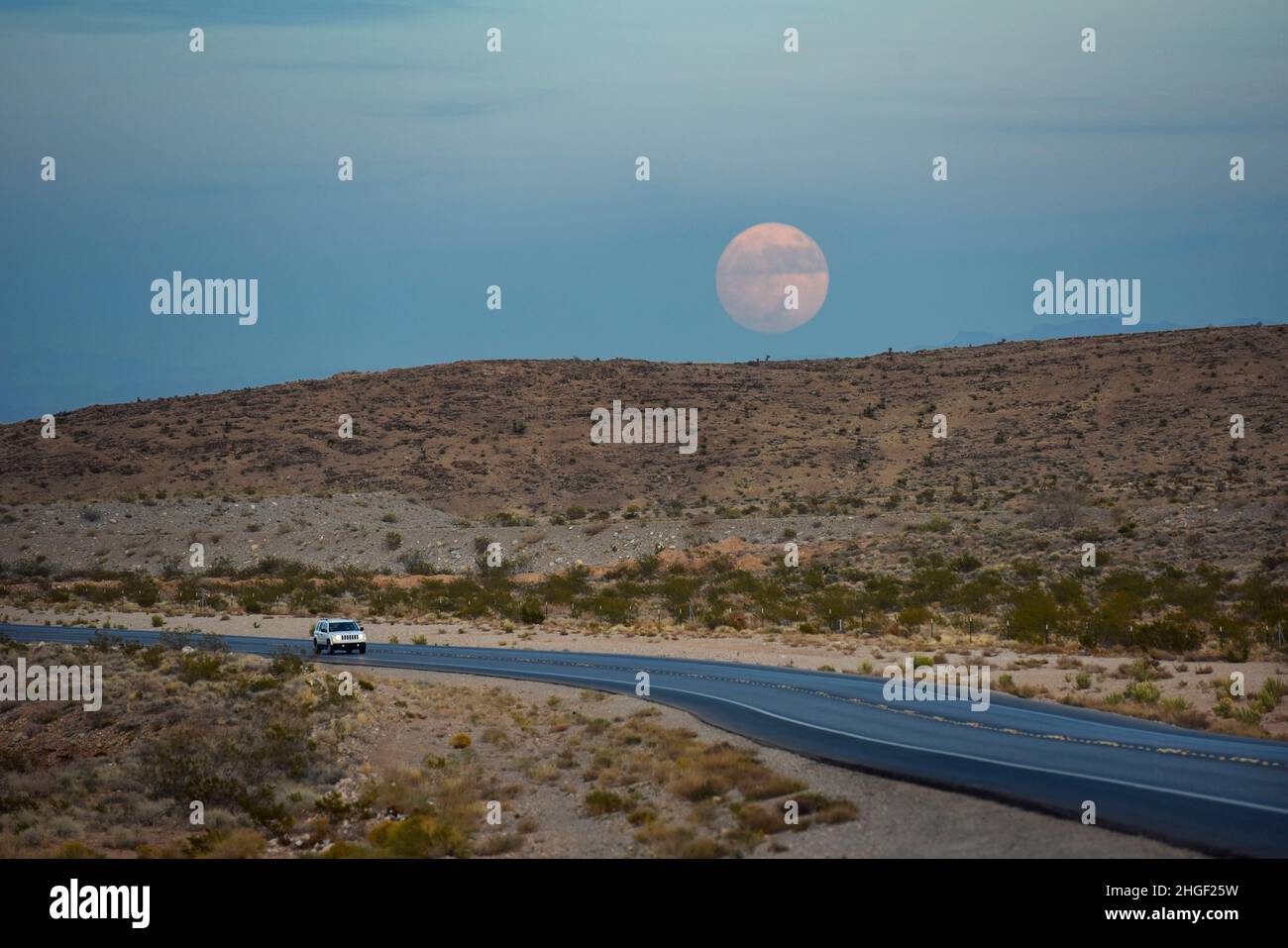 Südwestliche Wüste landsdape mit einem Vollmond und einem Jeep auf der Straße Stockfoto