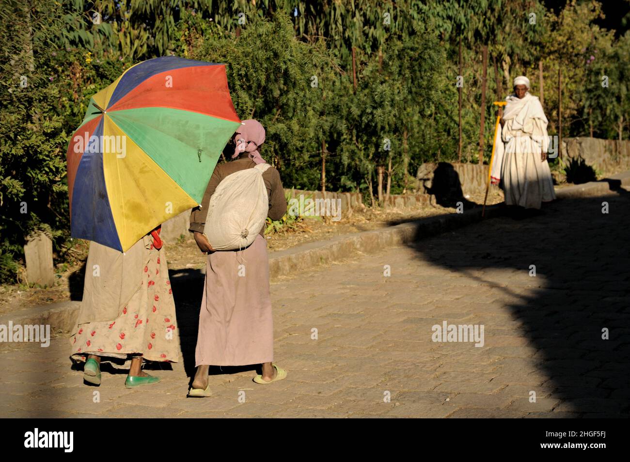 Frauen gehen mit einem bunten Regenschirm in Lalibela, Amhara Region, Äthiopien Stockfoto