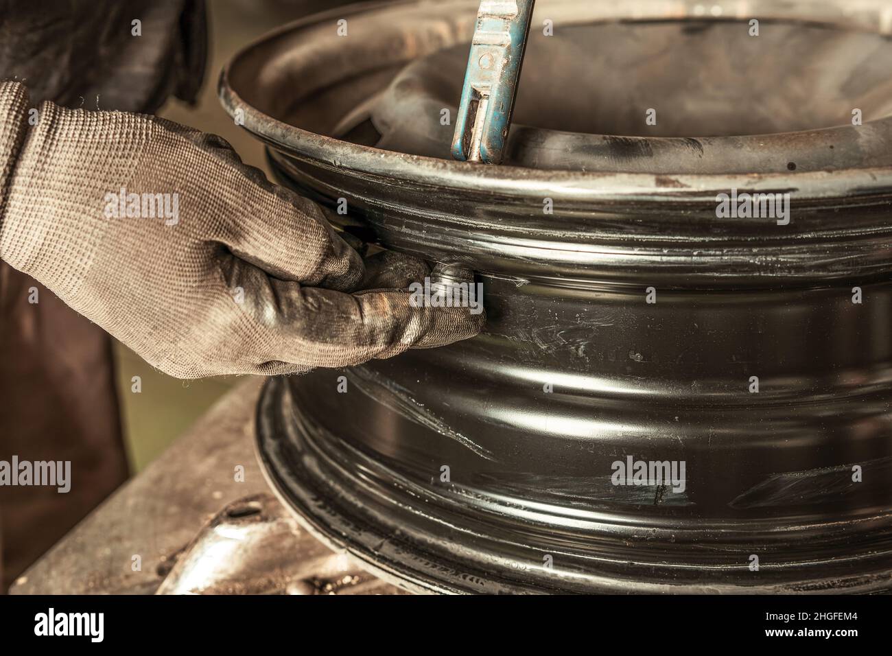 Mechaniker, der ein Ventil in ein Rad setzt, das er in Innenräumen repariert Stockfoto