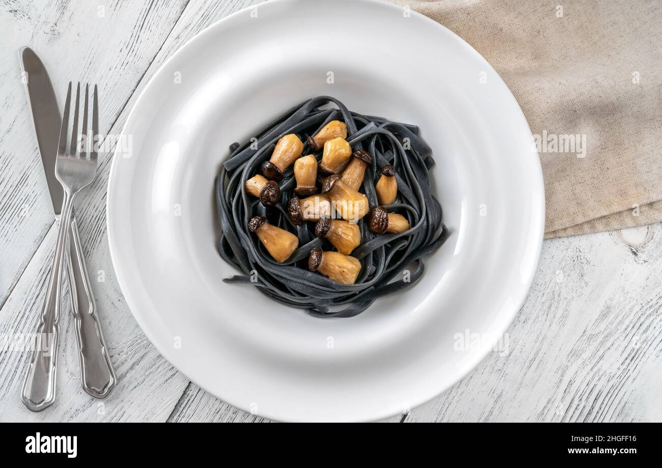 Tintenfisch Tinte Linguine Pasta mit Babypilzen Stockfoto