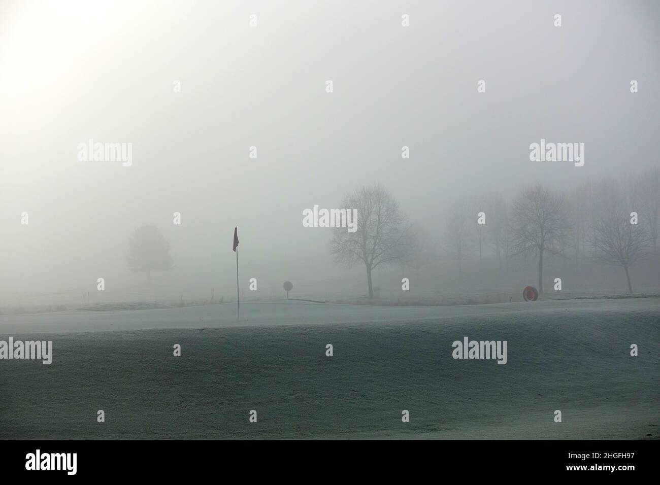 Blick auf den frühen Morgennebel, der an einem kalten Wintertag im Januar über einem Grün auf einem Golfplatz hängt Stockfoto