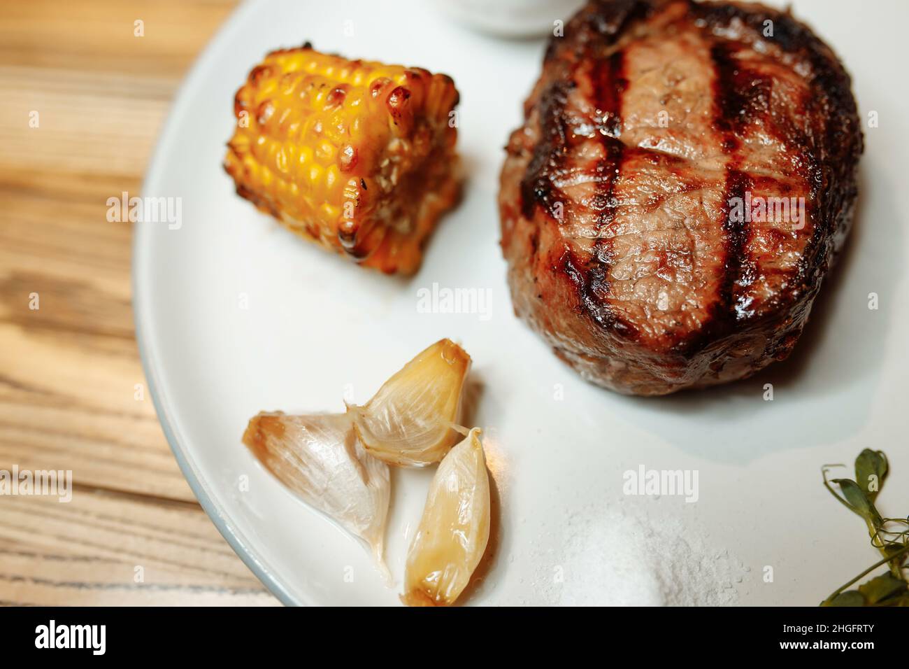 Gegrilltes Rib-Eye-Steak vom Grill, gebratenes Rib-Eye-Rindfleisch auf einem Teller mit grünem Salat. Dunkler Hintergrund Stockfoto