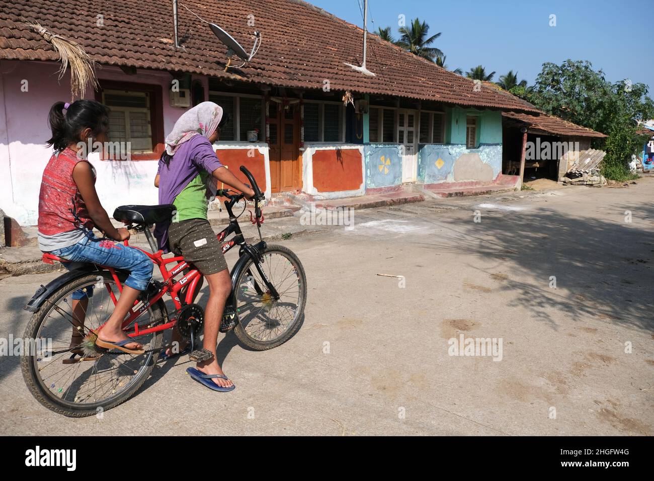 Karnataka, INDIEN 22. Dezember 2021, eine nicht identifizierte indische ländliche Mädchen mit ihrem Fahrrad. Spielzeit, ländliche Straße Stockfoto