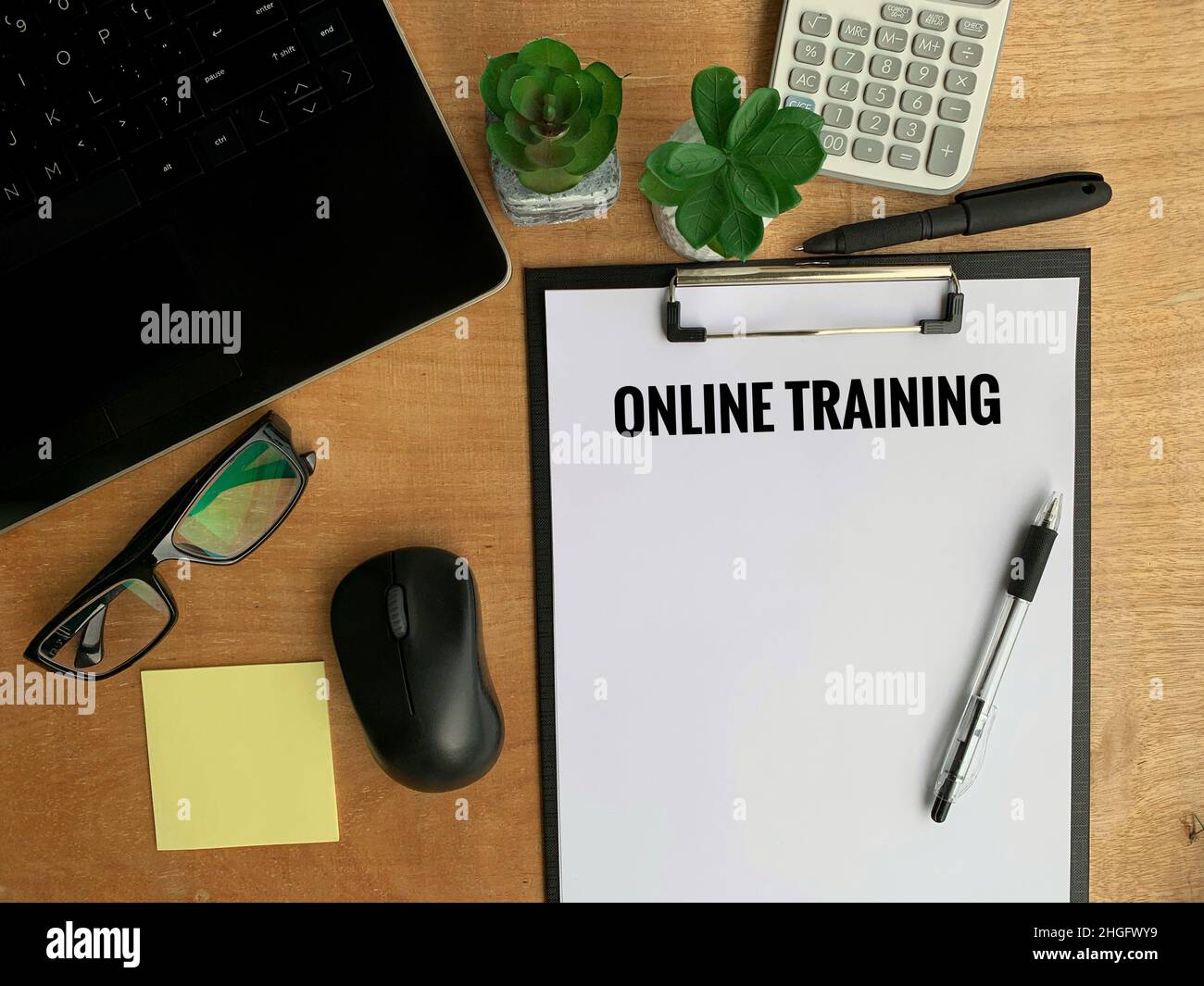 Online Business Concept Text - Online Training. Mit Laptop, Stift, Maus, Pflanze, Brille und braunem Tischhintergrund. Stockfoto