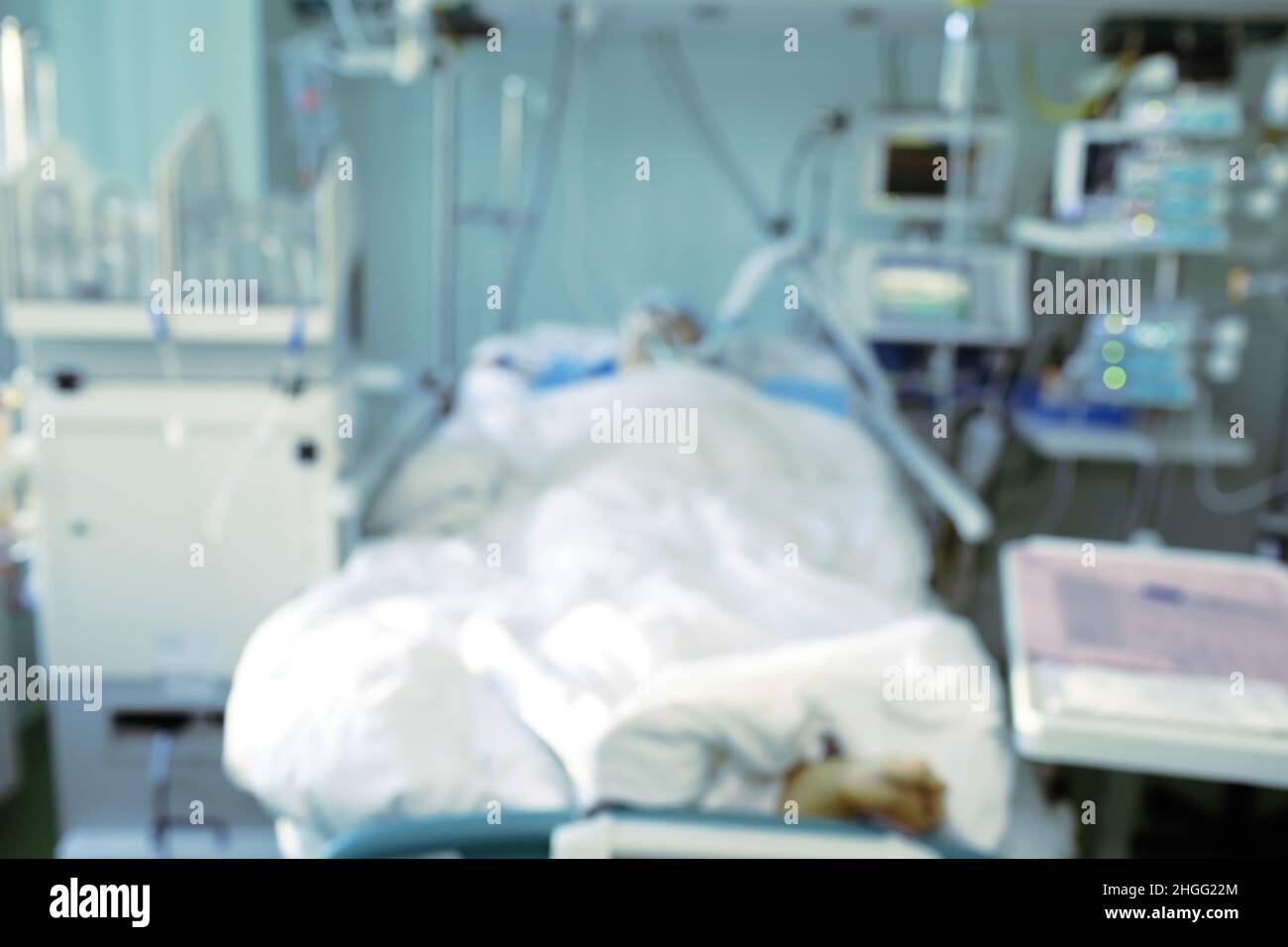 Verschwommene Silhouette eines bewusstlosen Mannes im Krankenhausbett, unfokussierter Hintergrund. Stockfoto