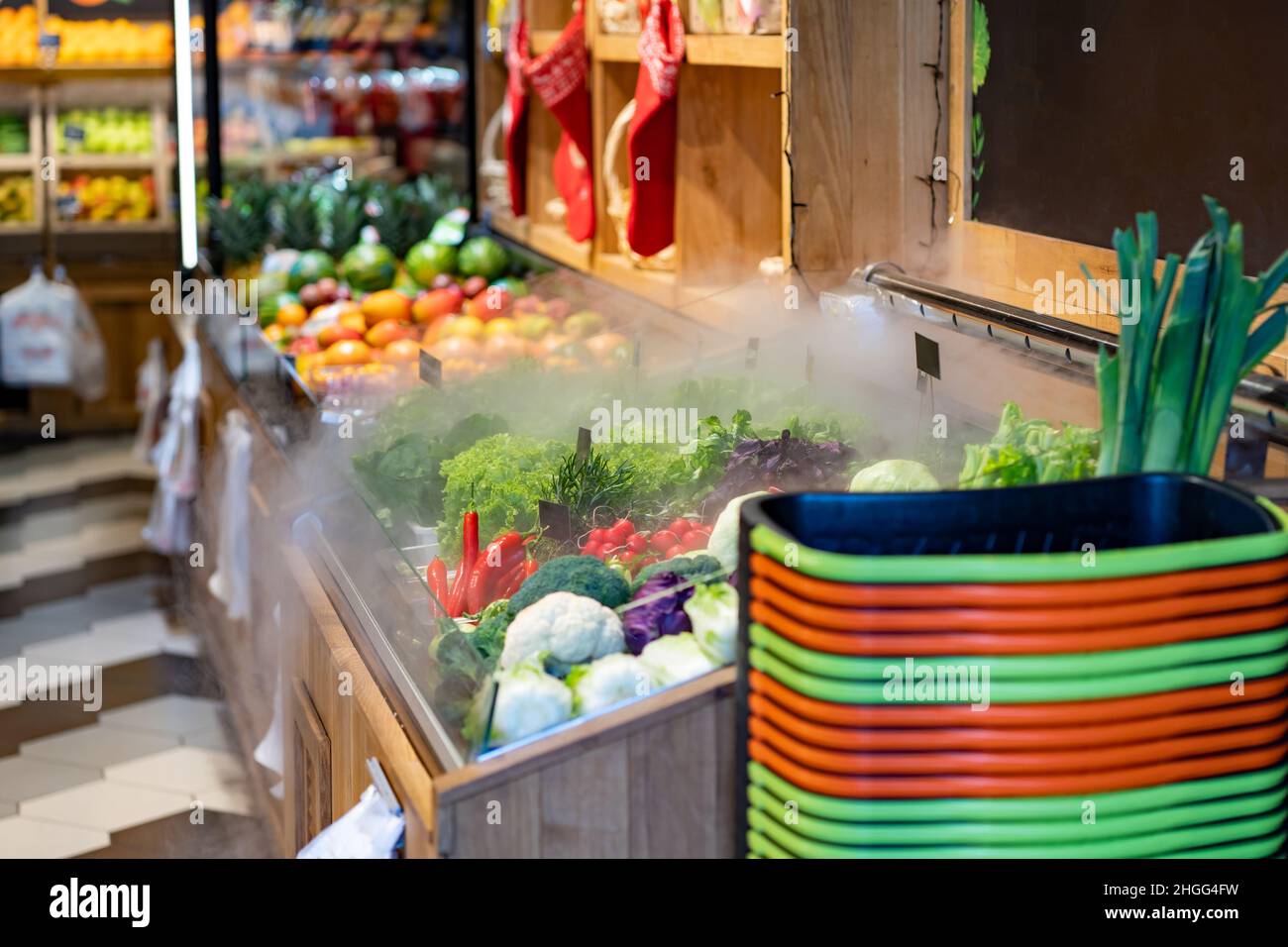 Lokaler Frischmarkt mit Obst und Gemüse in den Regalen. Einkaufskörbe. Befeuchter für Grünpflanzen. Stockfoto