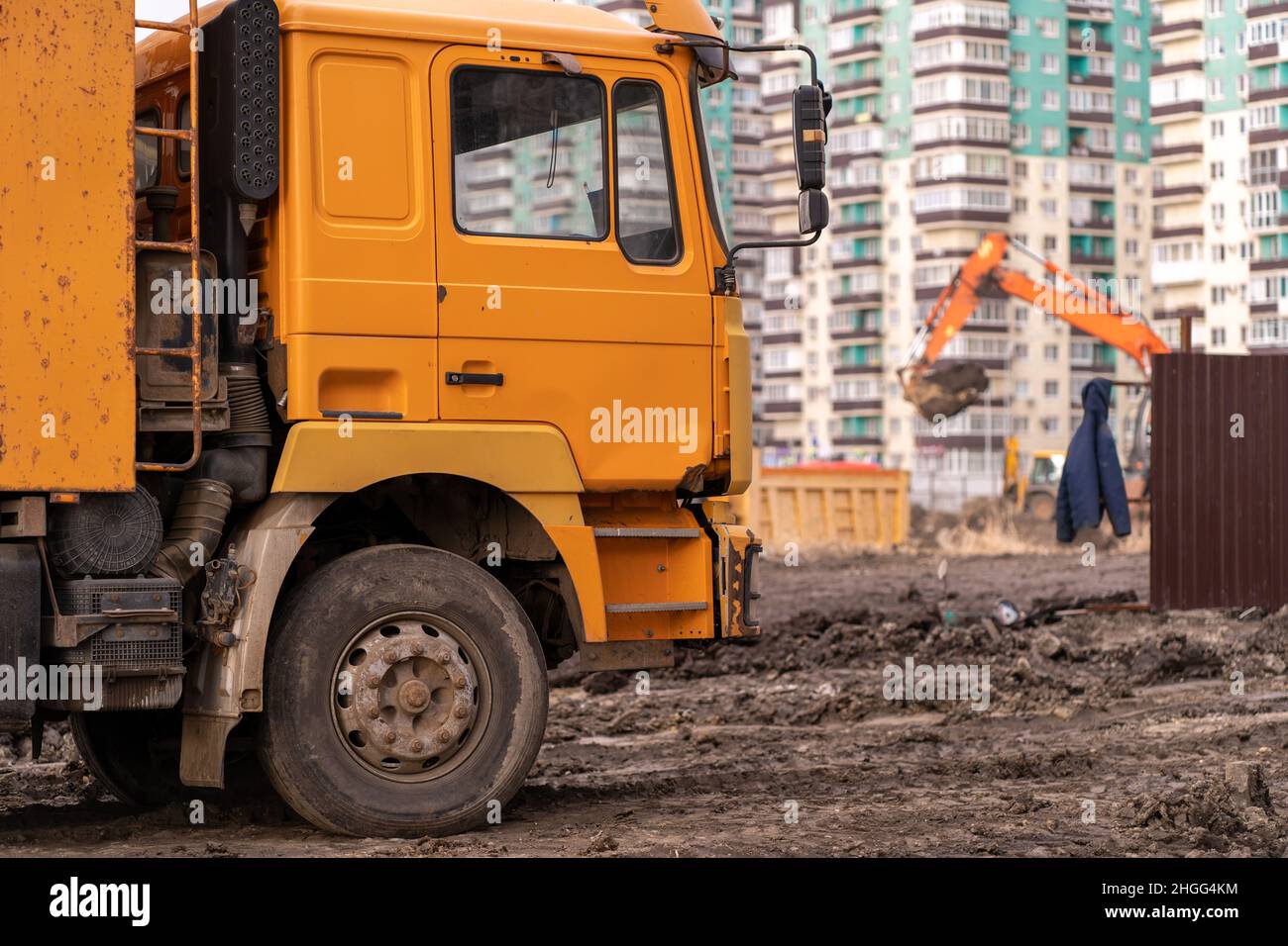 Bagger gräbt den Boden für die Gründung und den Bau eines neuen Gebäudes. Bagger beladen den Sand auf die Muldenkipper auf der Baustelle. Masse Stockfoto