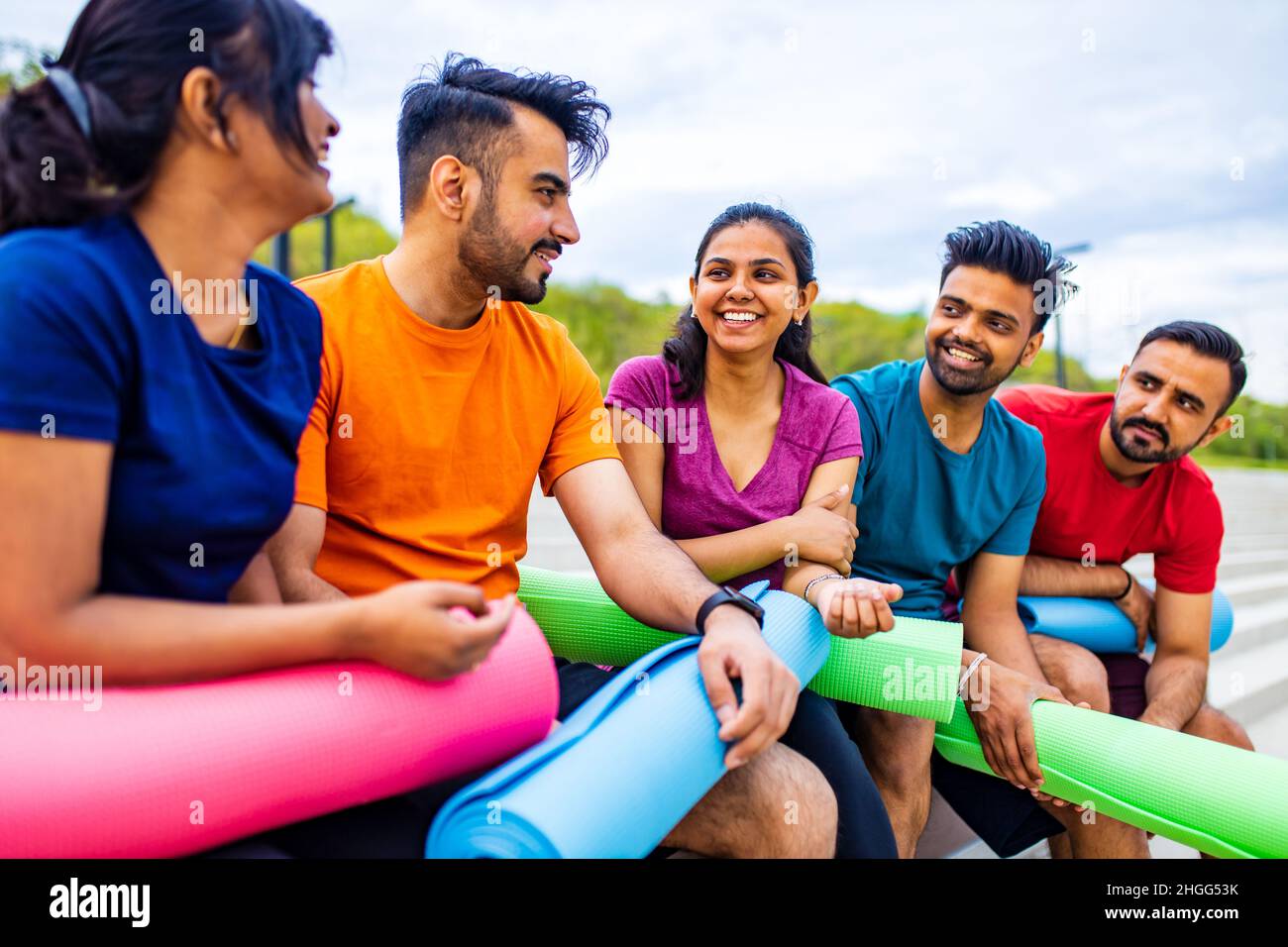 Gemischtes Rennen vier Menschen sprechen sfter Training in einem Yoga-Kurs außerhalb in Park Urban Stockfoto