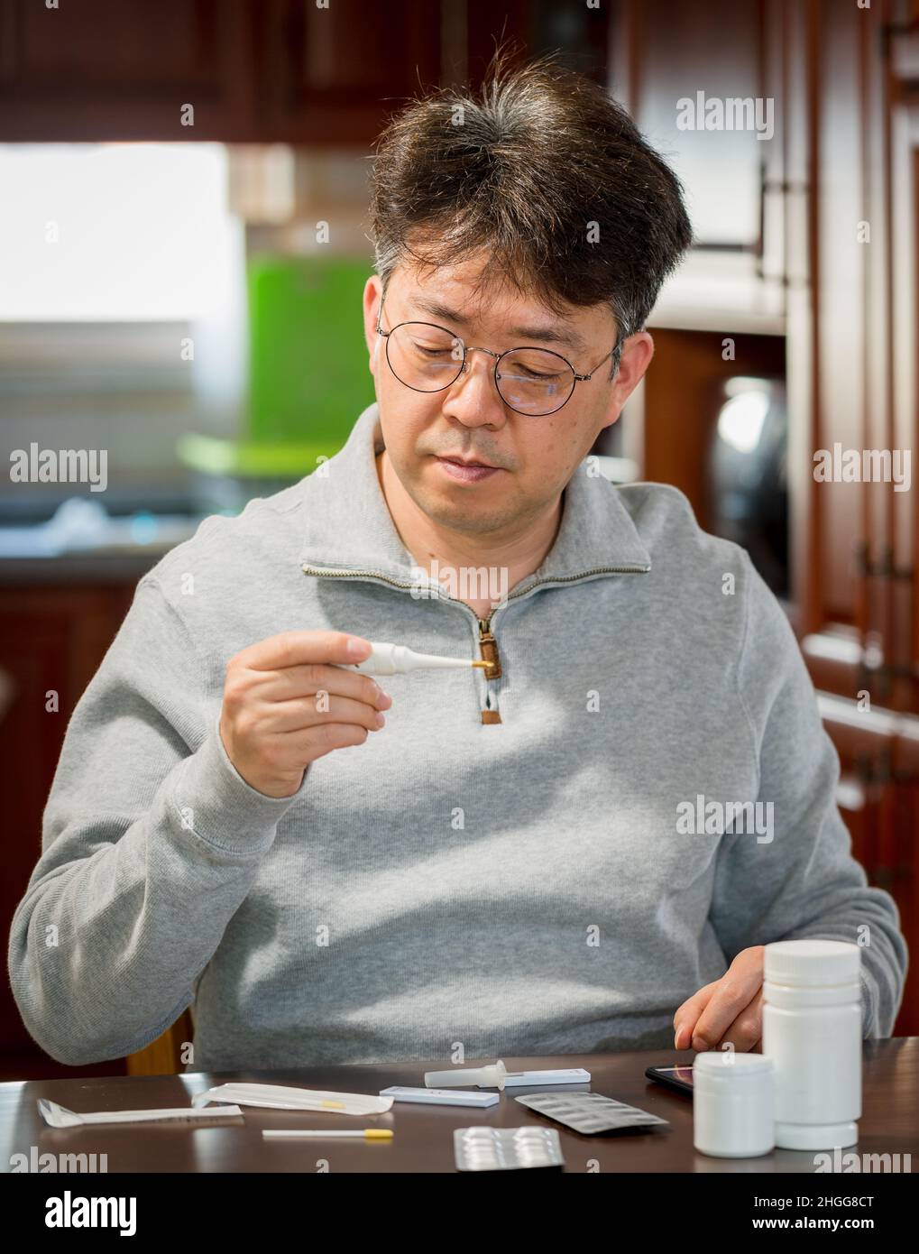 Ein asiatischer Mann mittleren Alters, der die Körpertemperatur zu Hause misst. Stockfoto