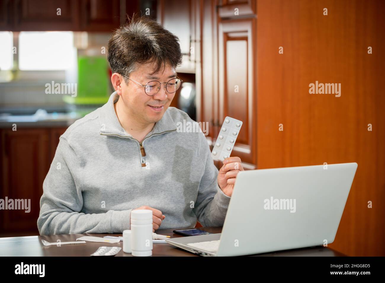 Asiatischer Mann mittleren Alters, der zu Hause Telemedizin erhält. Stockfoto