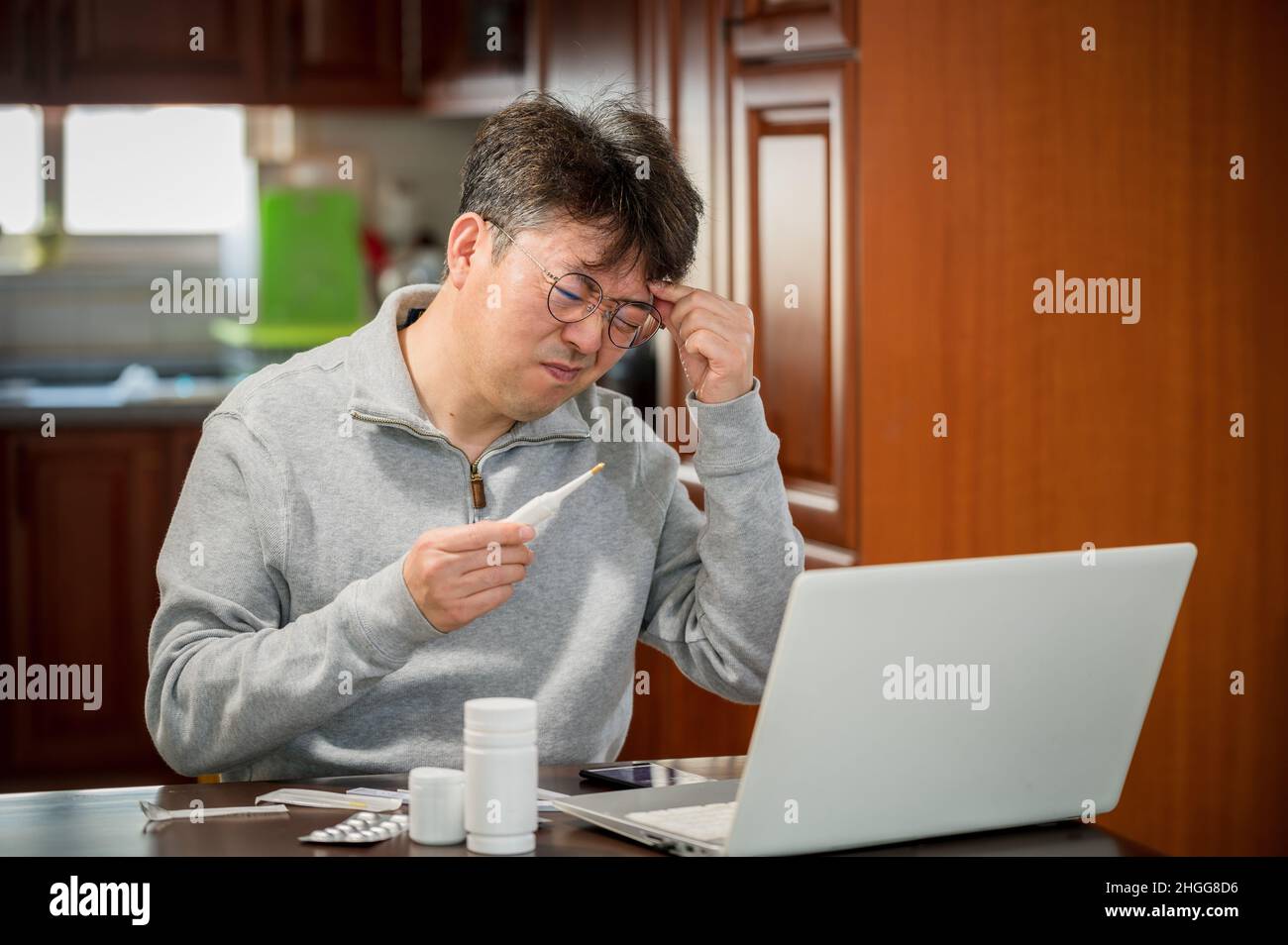 Asiatischer Mann mittleren Alters, der zu Hause Telemedizin erhält. Stockfoto