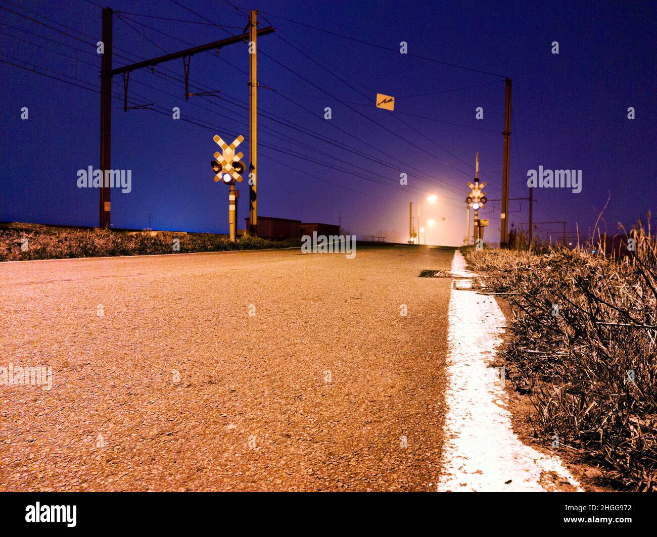 Flachwinkelfoto eines Bahnübergangs in einer nebligen Nacht ohne Personen Stockfoto