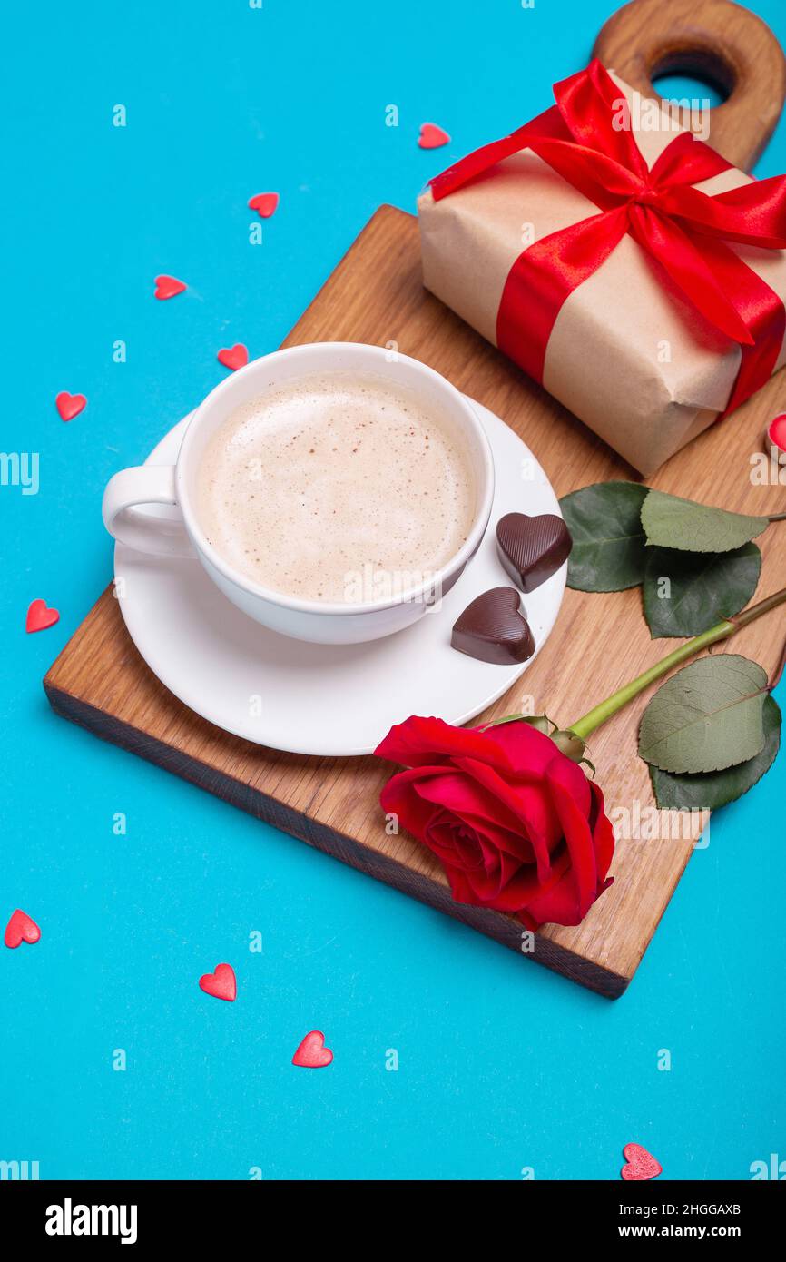 Valentinstag-Frühstück im Bett. Geschenk, Kaffeerose, Kerzen, Herzen auf blauem Hintergrund. Valentinstag-Konzept. Stockfoto