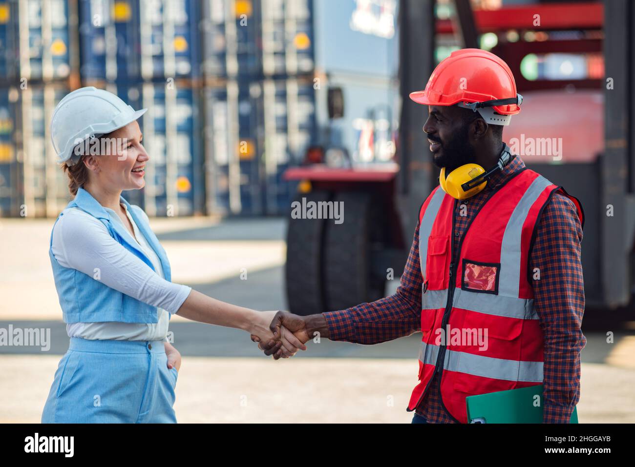 Happy Dealing schüttelt die Hände zwei Geschäftsfrau und Ingenieur arbeiten Überprüfung Verladecontainer Box von Cargo Frachtschiff für Import-Export. Shipping Stockfoto