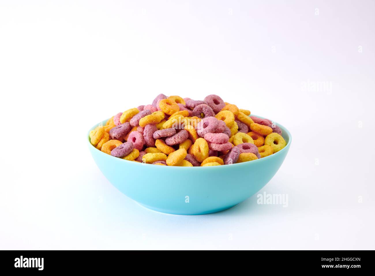 Ein Löffel mit bunten fruchtigen Cerealien und Milch auf einem verschwommenen Hintergrund Stockfoto