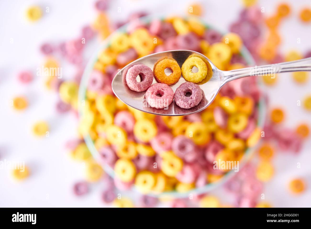Ein Blick von oben auf einen Löffel mit bunten fruchtigen Cerealien Und Milch auf einem verschwommenen Hintergrund Stockfoto