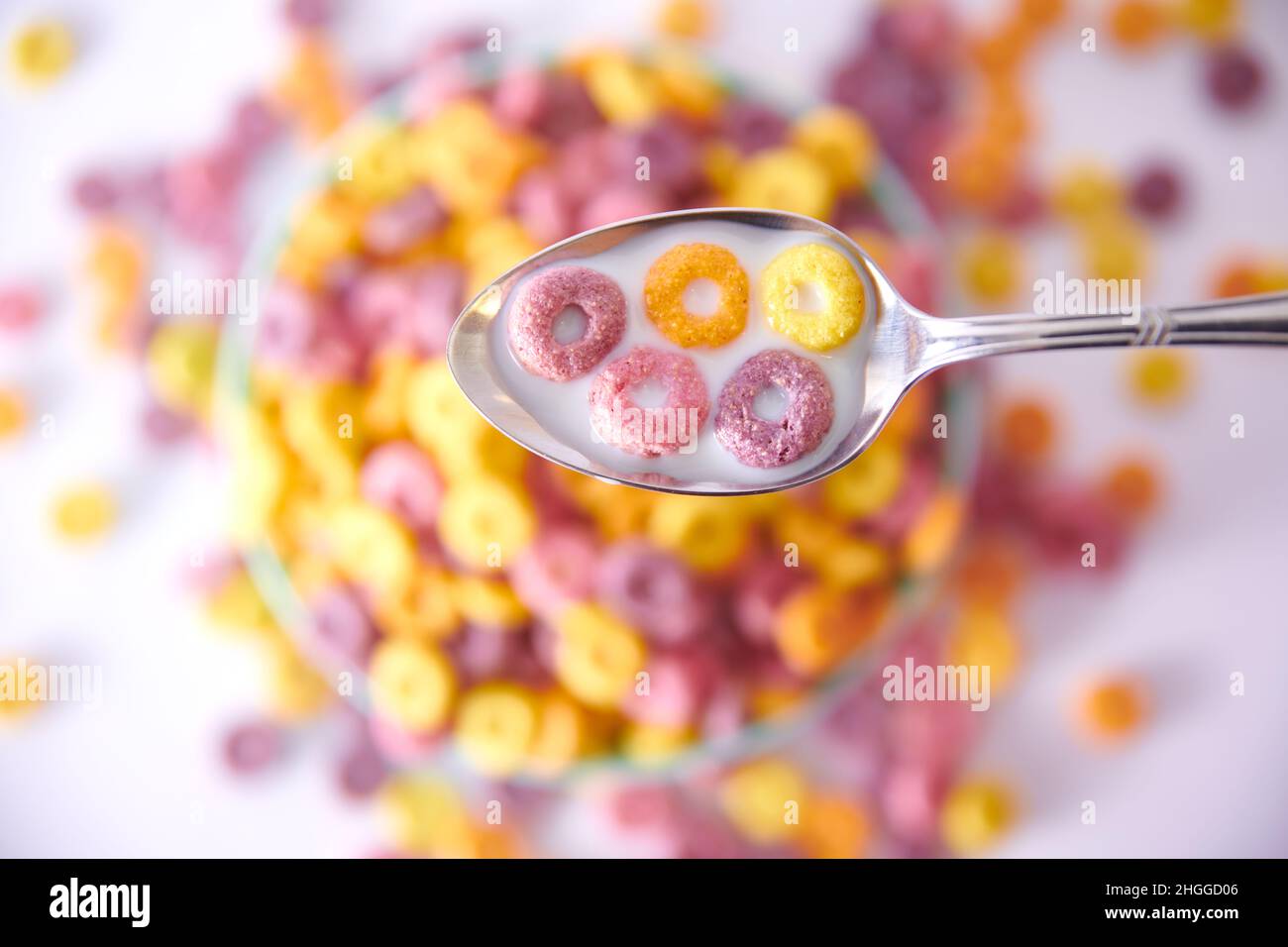 Ein Blick von oben auf einen Löffel mit bunten fruchtigen Cerealien Und Milch auf einem verschwommenen Hintergrund Stockfoto
