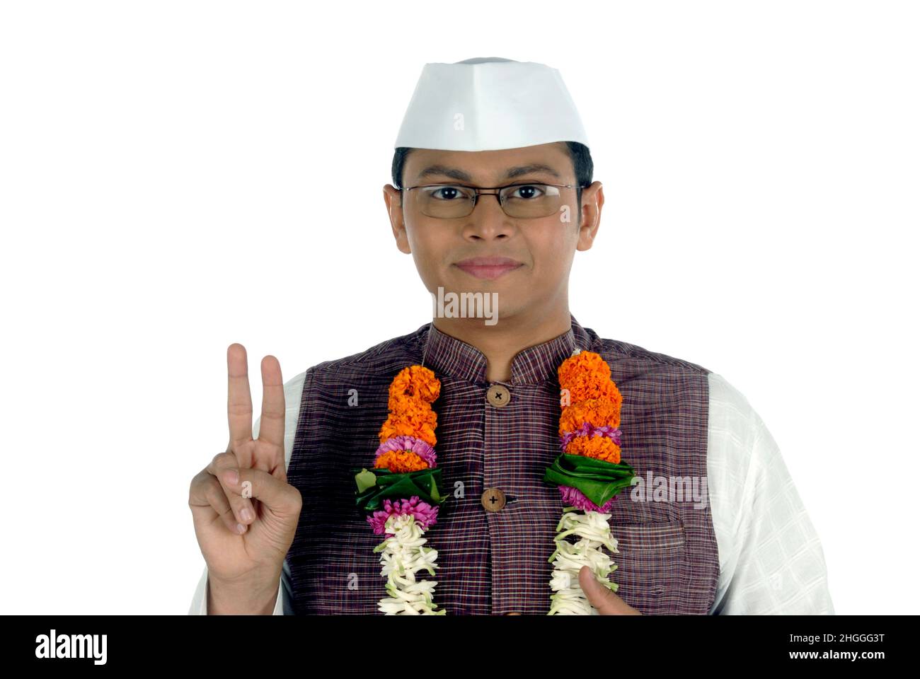 Mumbai; Maharashtra; Indien-Asien; 26. Dezember 2009 - Porträt eines jungen gutaussehenden lächelnden indischen Politikers, der ein Siegeszeichen mit weißem Hintergrund zeigt Stockfoto