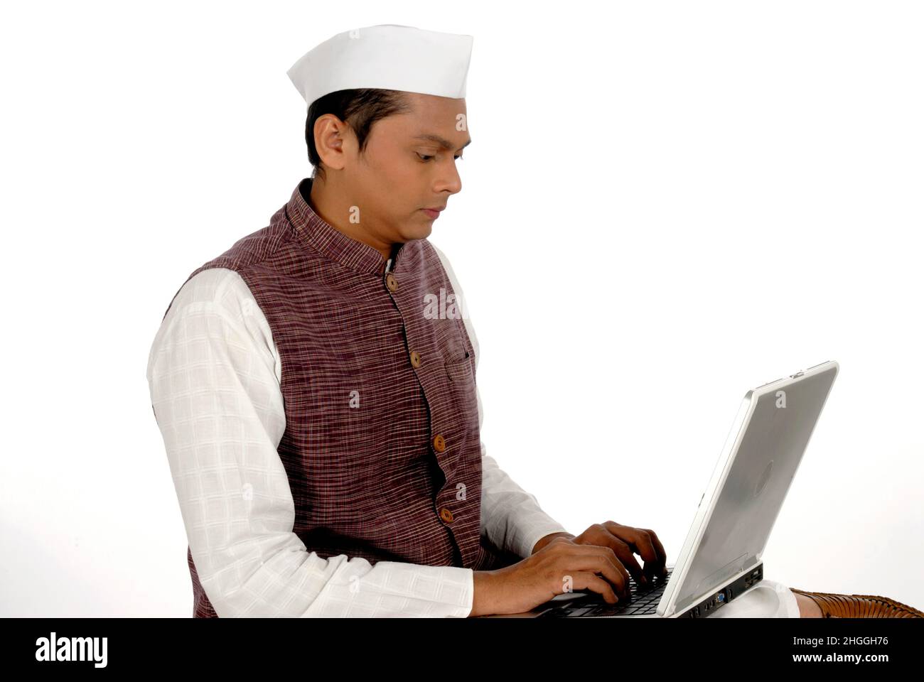 Mumbai; Maharashtra; Indien-Asien; 26. Dezember 2009 - Portrait junger gutaussehender lächelnder indischer Politiker, der mit Laptop-weißem Hintergrund arbeitet Stockfoto