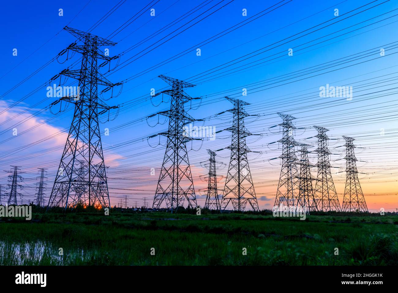 Hochspannungsturm-Industrielandschaft bei Sonnenaufgang, städtische Stromübertragungsleitungen. Stockfoto