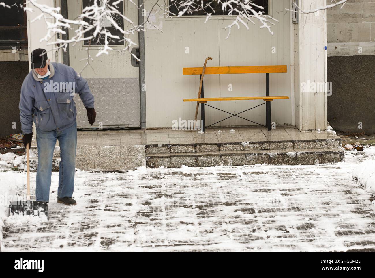 Die Leute reinigen Schnee und Eis vom Bürgersteig Stockfoto