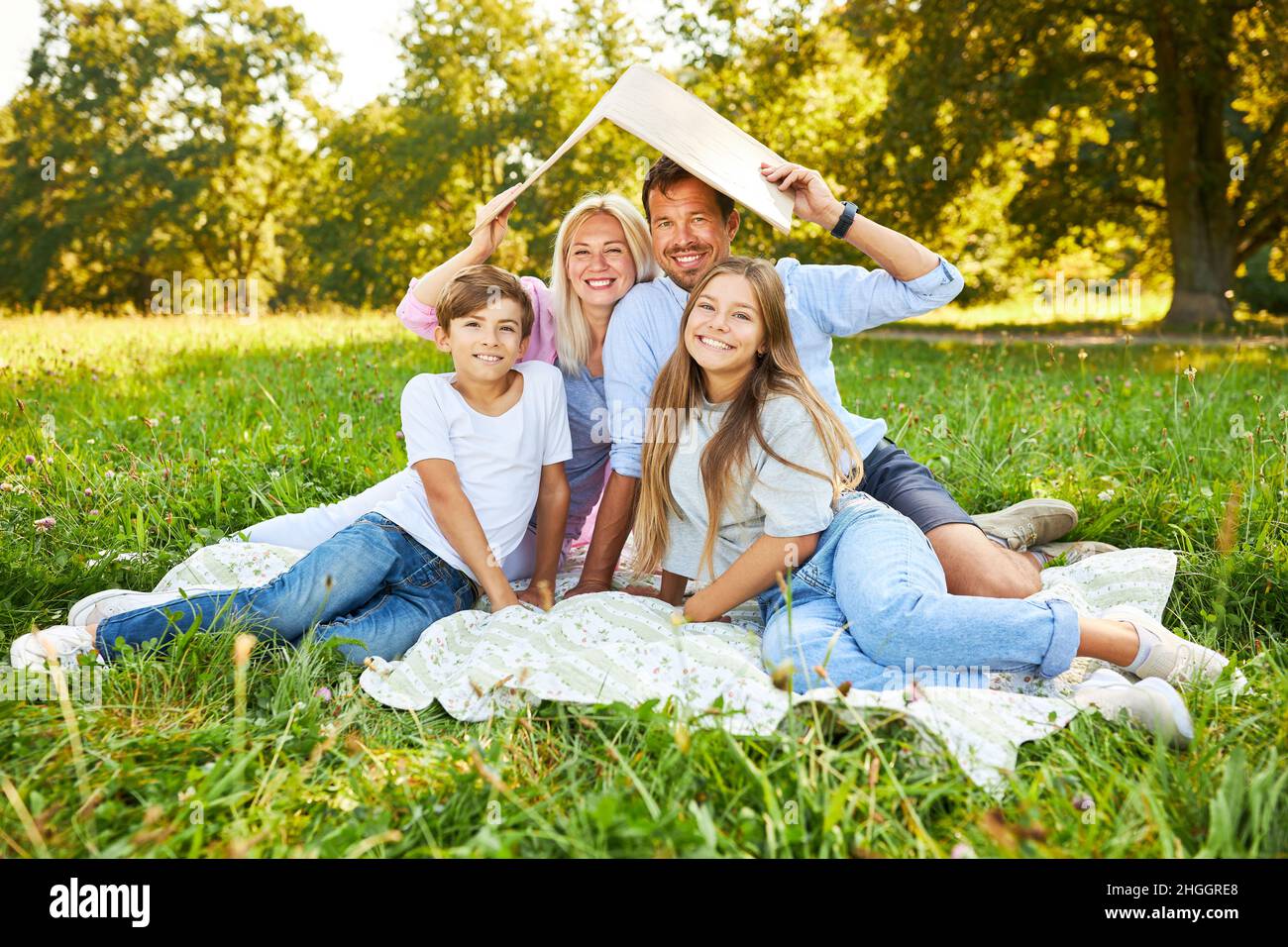 Glückliche Familie mit zwei Kindern und Dach über dem Kopf als Symbol für den Bau eines Hauses Stockfoto