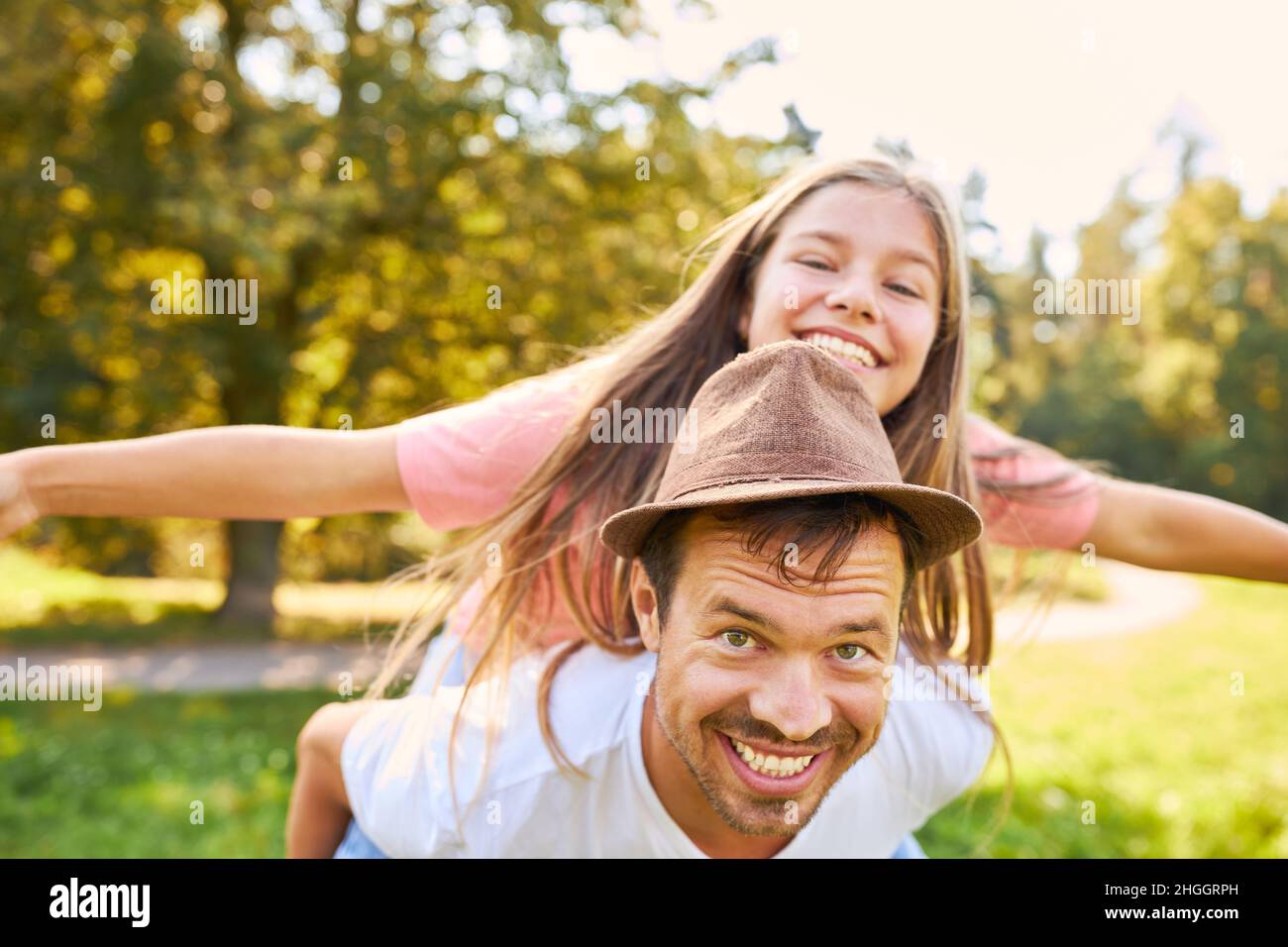 Vater mit Spaß Huckepack seine Tochter im Sommer in der Natur Stockfoto