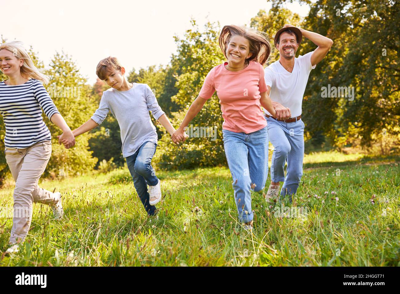 Eine glückliche Familie und zwei Kinder gehen im Sommer Hand in Hand über eine Wiese Stockfoto
