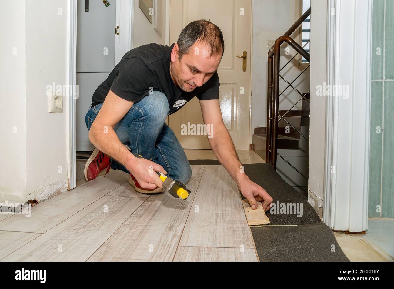 Arbeiter mit amputierten Fingern. Tagsüber arbeitet er an der Verlegung des Fußbodens in seinem Haus. Stockfoto