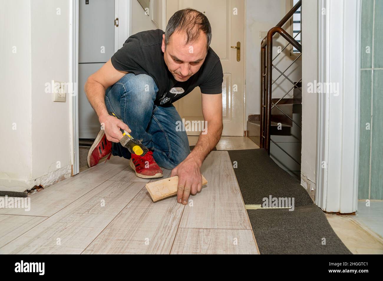 Arbeiter mit amputierten Fingern. Tagsüber arbeitet er an der Verlegung des Fußbodens in seinem Haus. Stockfoto